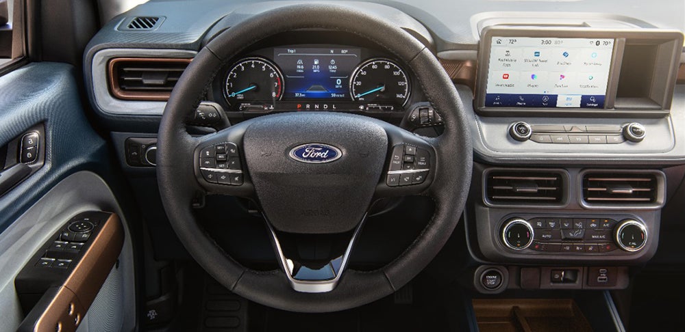 A Ford Bronco Sport highlighting its ground clearance and all-terrain tires as it navigates a dirt path through a lush forest.