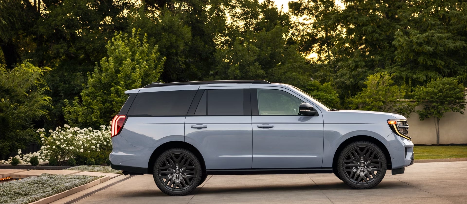 A blue 2026 Ford Expedition in Phoenix is parked facing right on a driveway with manicured trees in the background.