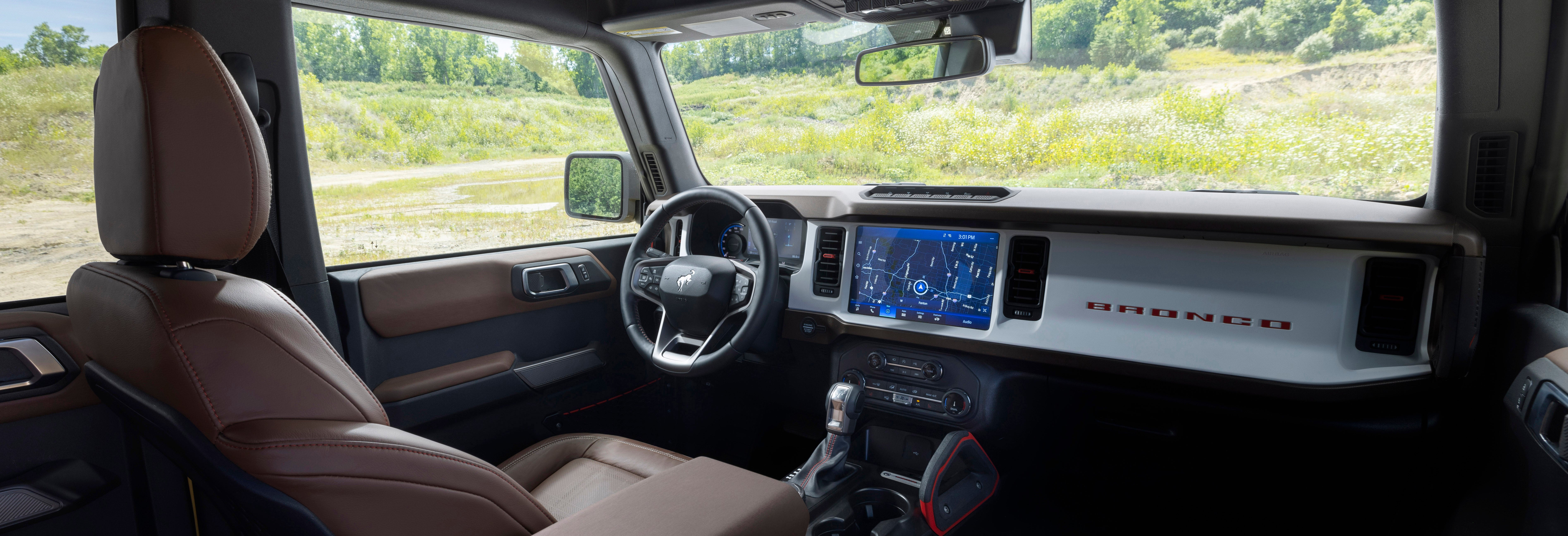 A red Ford Mustang convertible driving along a scenic coastal highway with the ocean and mountains in the background.