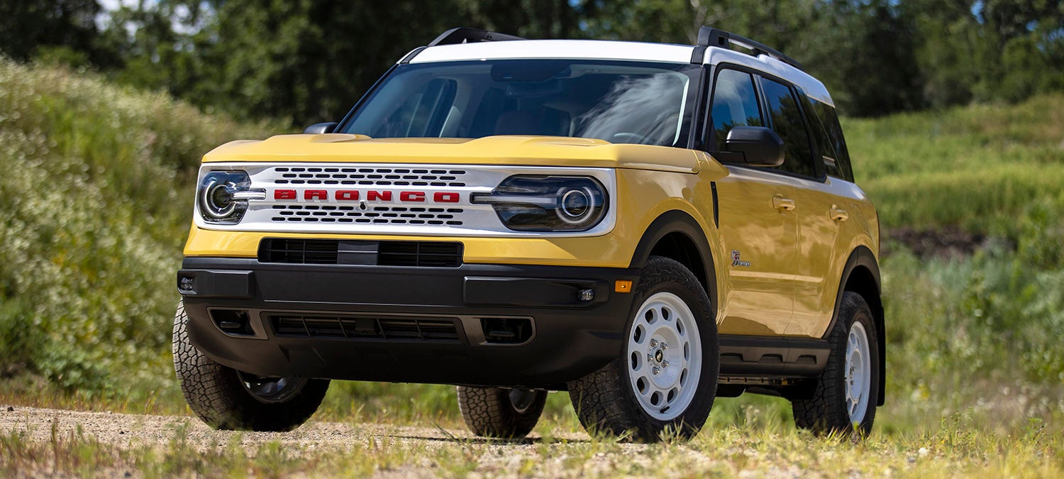 "Yellow Ford Bronco Sport SUV parked on a dirt road."