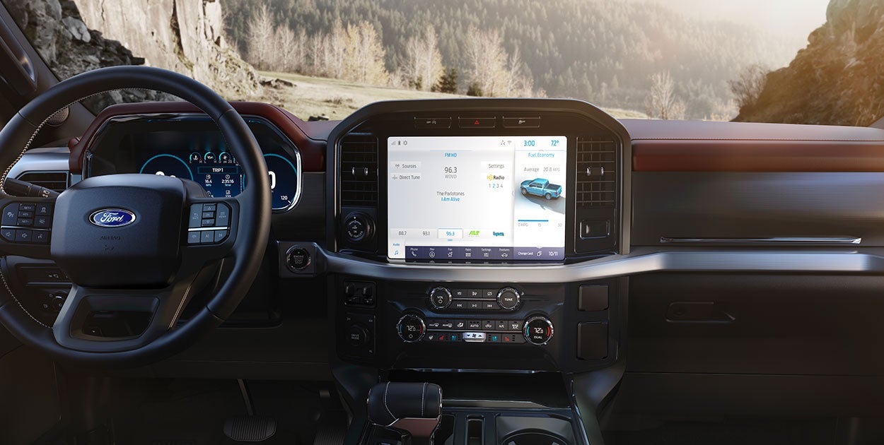 A Ford F-150 Tremor highlighting its lifted suspension and all-terrain tires as it navigates a forest path.